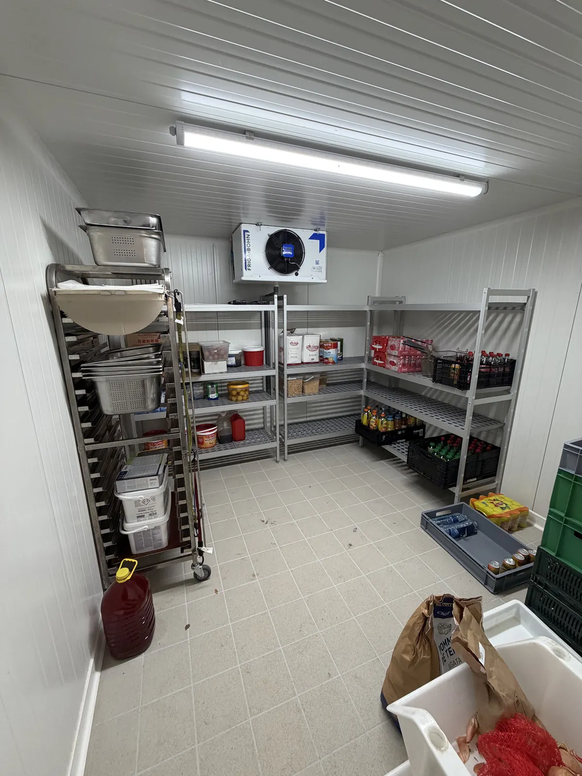 Intérieur d'une chambre froide positive équipée de rayonnages inox et d'un évaporateur au plafond.